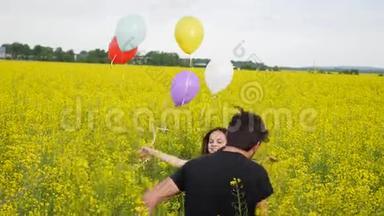 穿着裙子的小女孩手里拿着气球穿过黄色的麦田。 缓慢的动作